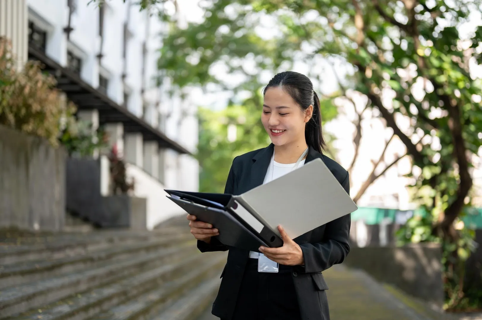 East Asian businesswoman reviewing qualification documents in a city setting
