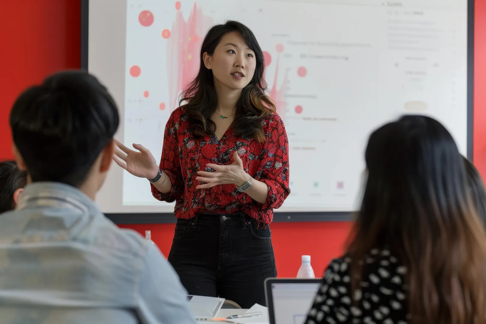 East Asian woman presenting a project to colleagues in a modern office