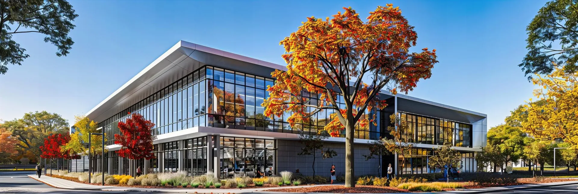 Modern university campus building with glass facade and autumn trees
