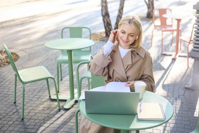 East Asian student working on a laptop at an outdoor cafe